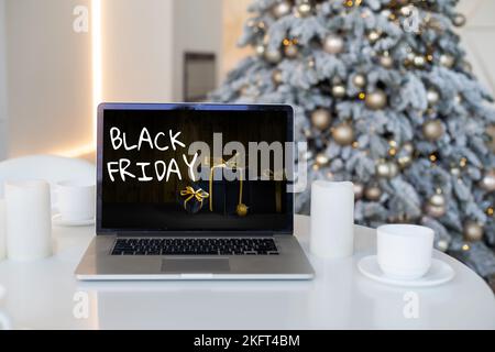 Concetto di shopping del Black Friday scritto sullo schermo nero del notebook contro lo sfondo sfocato delle luci di natale Foto Stock