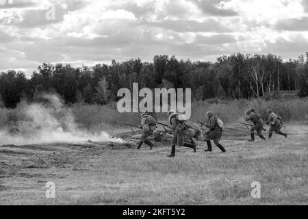 L'attacco di soldati sovietici sul campo, in bianco e nero. Fumo dalle pistole. Ricostruzione della battaglia della seconda guerra mondiale Russia, regione di Chelyabinsk Foto Stock