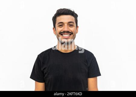 Uomo positivo con baffi in piedi su sfondo isolato in t-shirt nera sorridendo e guardando la macchina fotografica Foto Stock