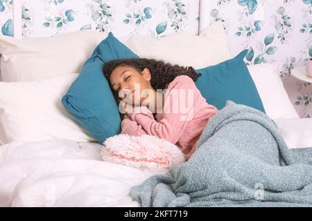 Giovane zoomer latino-americana con capelli scuri in pigiama sdraiato su un morbido letto e addormentato a casa Foto Stock