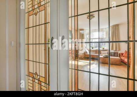 Interno di una spaziosa zona salotto con mobili in vecchio stile progettati in stile vintage in una casa residenziale dietro una porta di vetro Foto Stock