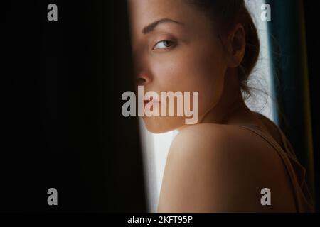 Vista laterale di una donna pensiva che si rilassa accanto alla finestra Foto Stock