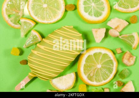 Gelato giallo su un bastone, banane e limoni su sfondo verde, vista dall'alto Foto Stock