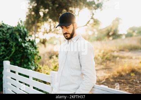 Ritratto di un giovane uomo bearato che indossa un berretto nero in campagna Foto Stock