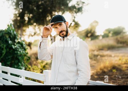 Ritratto di un giovane uomo bearato che indossa un berretto nero in campagna Foto Stock