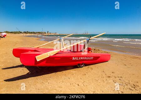 Un catamarano a remi rosso salvataggio pronto a salvare i nuotatori su una spiaggia in Sicilia Foto Stock