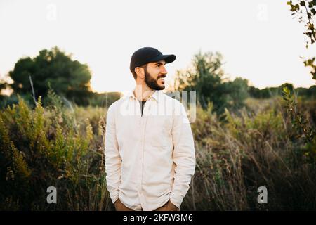 Ritratto di un giovane uomo bearato che indossa un berretto nero in campagna Foto Stock