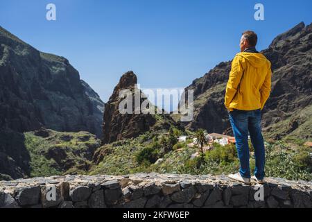 Canyon Masca nel comune di montagna di Tenerife, Isole Canarie. L'uomo turistico di mezza età gode della vista del villaggio, gola di roccia e le cime del Foto Stock