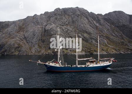 Antigua Barquentina entrando nel porto di Nusfjord che è un piccolo e pittoresco, ma molto turistico pesca villige sull'arcipelago norvegese Lofoten. Foto Stock