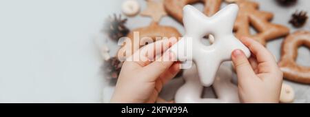 Le mani dei bambini tengono un pan di zenzero a forma di stella. Il concetto di dolci natalizi, giocattoli, ghirlande e bokeh. Arredamento per le vacanze di Capodanno. Foto Stock