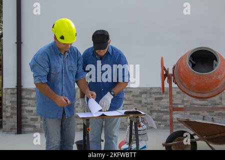 Immagine di un ingegnere e di un lavoratore di costruzione in un cantiere di costruzione mentre consultano il piano del progetto da realizzare. Foto Stock