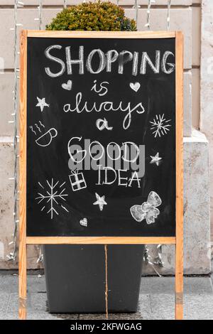 Lo shopping è sempre un cartello commerciale di buona idea scritto su una lavagna con disegni festosi di fronte a un negozio nel centro della città Foto Stock
