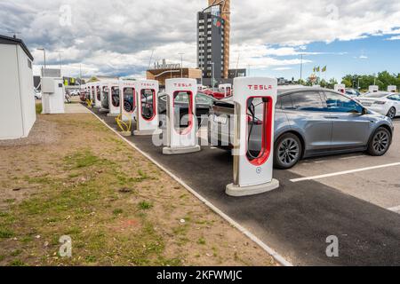 Halmstad, Svezia - 10 2022 luglio: Lunga fila di auto Tesla in carica presso il Tesla Supercharger Halmstad Foto Stock