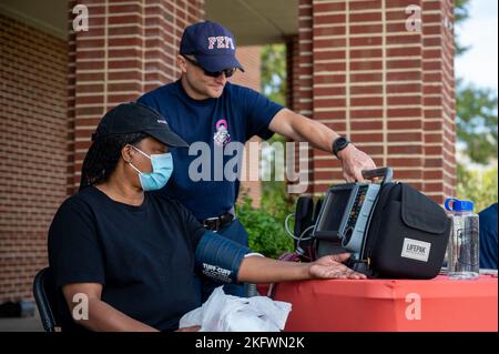 Kevin Hall, Fort Eustis Fire and Emergency Services pompiere paramedic, amministra un controllo libero della pressione sanguigna su Annie Hollis alla base comune Langley-Eustis, Virginia, 12 ottobre 2022. I servizi antincendio e di emergenza hanno offerto controlli gratuiti della pressione sanguigna presso il commissario per promuovere il benessere e la sicurezza all'interno della comunità. Foto Stock