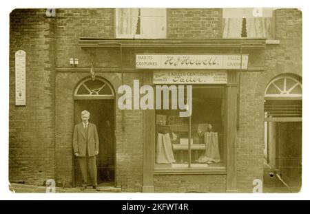 Cartolina originale dell'era WW1 del proprietario/sarto elegantemente vestito, in piedi nella porta fuori un negozio boutique - ci è un segno per impermeabilizzazione di Burberry nella finestra e le lunghezze di tweed. Il segno sopra dichiara H J Howell Ladies and gentes sarti & anche pubblicità sartoria di 'costumi, abitudini., braghe & liveries' il segno inoltre fa pubblicità ad altri locali a 11 Milk St Cheapside London. Ma c'è una centrale telefonica sul cartello per Arundel 25 - così questo negozio si trova nella città costiera del Sussex occidentale di Arundel in High Street - forse si è ritirato qui e ha conservato il negozio di Londra. Circa 1917, Regno Unito Foto Stock