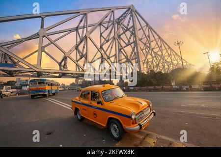 Taxi parcheggiato sulla strada cittadina con vista sullo storico ponte Howrah Kolkata, India all'alba. Foto Stock