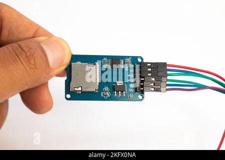 Un modulo lettore di schede microSD con il relativo cavo di collegamento è tenuto in mano. Questo modulo viene utilizzato per gli appassionati di elettronica di materiali fai da te. Foto Stock