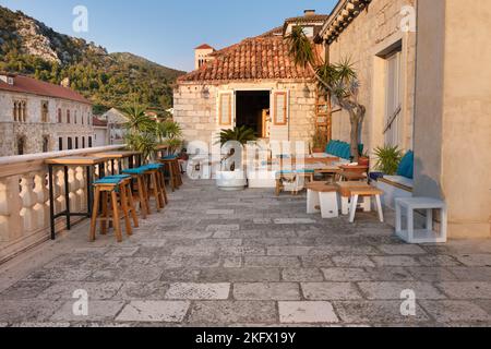 Accogliente terrazza all'aperto caffè all'aperto nella città di Hvar, Croazia. Architettura tradizionale croata. Tavoli e sedie nel patio all'aperto al di fuori del caffè o. Foto Stock