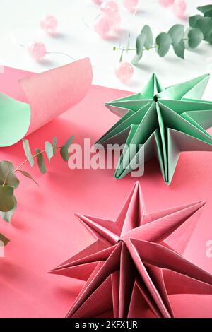 Vibranti stelle di carta origami, decorazioni natalizie fai da te fatte a mano. Stelle natalizie fatte da soli realizzate in carta colorata su sfondo stratificato. Fatto a mano Foto Stock