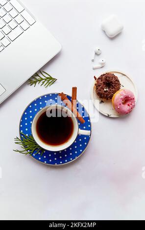 Stile di vita con computer portatile, auricolari wireless, tazza da caffè con ciambelle. Corso online, imparare la lingua, freelance. Webinar, lavoro online, ascolto Foto Stock