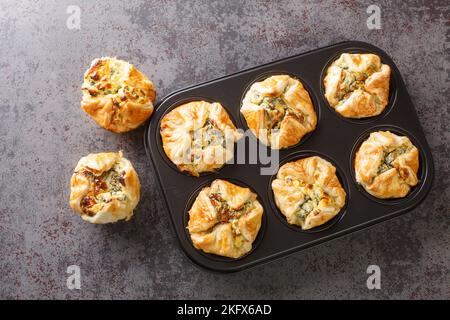 muffin al formaggio feta fatti in casa con closeup di spinaci nella padella per impaffini sul tavolo. Vista orizzontale dall'alto Foto Stock