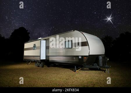 Camper su un punto erboso con stelle luminose sopra Foto Stock