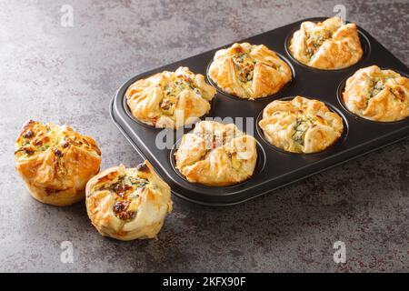 muffin al formaggio feta fatti in casa con closeup di spinaci nella padella per impaffini sul tavolo. Orizzontale Foto Stock