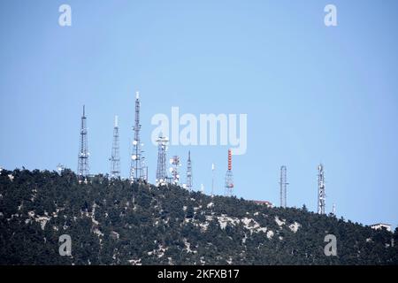 Antenne per telecomunicazioni sul monte Parnitha con alberi e cielo blu Foto Stock