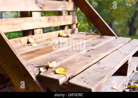 La panca del pallet in legno si trova sul vicolo del parco, paesaggio autunnale Foto Stock