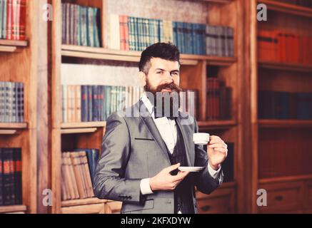 Concetto di caffè e successo. Uomo bearded in costume costoso beve caffè Foto Stock