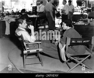 PAUL MUNI e sua moglie BELLA MUNI su set candid con Movie / Film Crew durante le riprese di HI, NELLIE ! 1934 regista MERVYN Leroy regista Sol Polito Warner Bros. Foto Stock