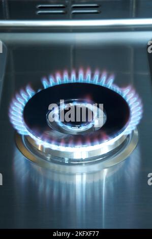 Fiamme blu bruciano da un getto di gas acceso sul piano cottura di una cucina. Il gas naturale, costituito principalmente dal metano, porta calore al 85% delle famiglie britanniche. Foto Stock