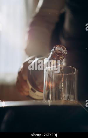Uomo che versa whisky al bancone bar in legno, bere a casa notte. Foto Stock