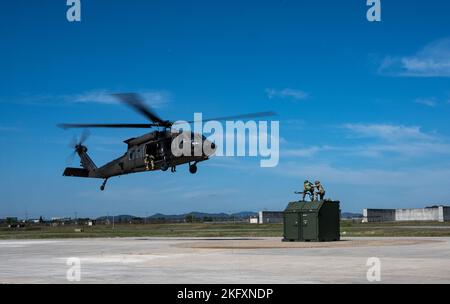 Staff Sgt. Brayken Bortolotti e Airman 1st Class Robert Pillsbury, 25th Capi dell'equipaggio Fighter Generation Squadron, aspettano di assicurare un'unità interna Slingable a un elicottero Black Hawk dell'esercito degli Stati Uniti durante un addestramento integrato a carico di imbracatura presso Osan Air base, Repubblica di Corea, 13 ottobre 2022. I capi equipaggio si sono offerti volontariamente per l'addestramento al carico di imbracatura come parte del piano Agile Combat Employment dell'USAF per produrre Airmen multi-capaci che eseguono regolarmente compiti al di fuori della loro specialità abituale per essere più ben arrotondati. Foto Stock