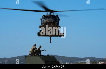 Senior Airmen Giancarlo Hernandez e John Millan-Irizarry, 51st manutenzione Squadron Aerospace Ground Equipment i viaggiatori, aspettano di assicurare un'unità interna Slingable Unit ad un elicottero Black Hawk dell'esercito statunitense durante un addestramento integrato a carico di imbracatura presso Osan Air base, Repubblica di Corea, 13 ottobre 2022. Le operazioni di carico di imbracatura possono essere utilizzate per le contingenze per disperdere le risorse in posizioni operative più piccole. Foto Stock