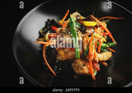 Pollo in stile cinese con funghi e verdure, su sfondo scuro. Panasia Foto Stock