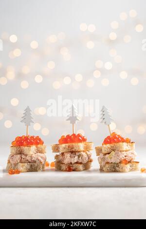 Canape all'albero di Natale con salmone affumicato, formaggio cremoso, aneto, piatto di rafano e caviale rosso per uno spuntino natalizio Foto Stock