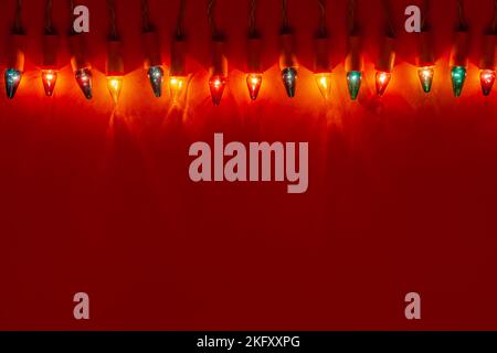 Colorful Christmas Lights - lampadine retrò di diversi colori su sfondo rosso con grande spazio di copia Foto Stock