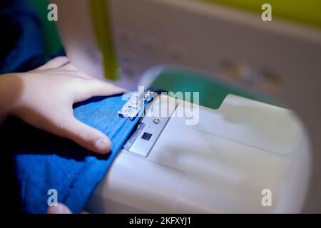 Le mani di una giovane ragazza che cucita su una macchina da cucire. Il concetto di piccola impresa, hobby, ricreazione domestica. Eco, zero rifiuti, riciclaggio. Foto Stock