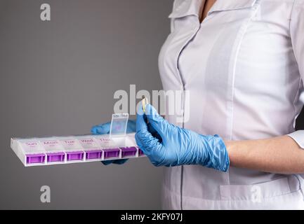 Medico con contenitore per pillola, organiser compresse con capsula omega in mano. Concetto di prescrizione medica. Foto di alta qualità Foto Stock