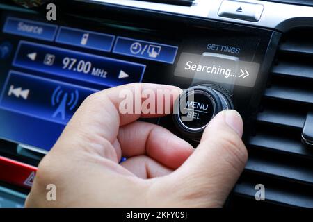 Il conducente regola la mano per cercare una stazione radio sul cruscotto dell'autoradio Foto Stock