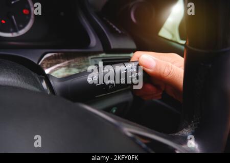 La mano del conducente attiva la leva del commutatore proiettori Foto Stock