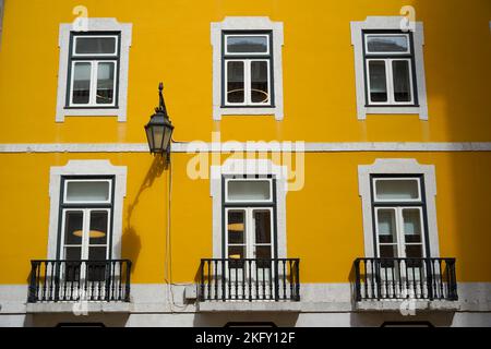 Set di finestre europee classiche contro un muro dipinto di giallo luminoso, edificio storico Foto Stock