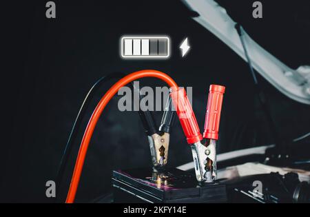 Ricarica della batteria dell'auto e un'icona di ricarica illuminata nel garage di riparazione automatica Foto Stock