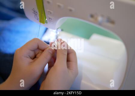 Le mani di una giovane ragazza che cucita su una macchina da cucire. Il concetto di piccola impresa, hobby, ricreazione domestica. Eco, zero rifiuti, riciclaggio. Foto Stock