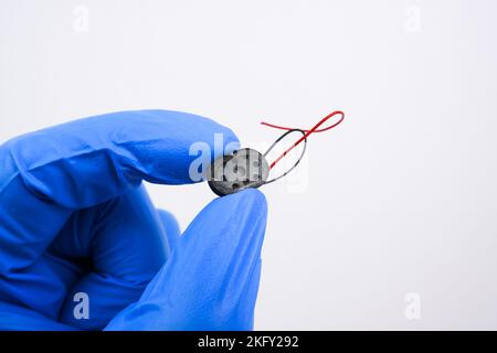Piccole parti dell'altoparlante in una mano per piccoli apparecchi e smartphone su sfondo bianco Foto Stock