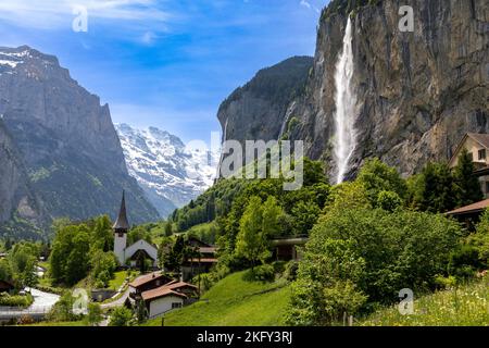 Vista panoramica di una parte di Lauterbrunnen in Svizzera. Le Alpi innevate sullo sfondo e la cascata Staubbach sulla destra. Foto Stock