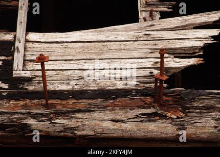 Una grande, vecchia, naufragata barca di legno, in bacino a secco, che mostra i putrefoli di legno, noci e bulloni e metallo come è lentamente disintigraente Foto Stock