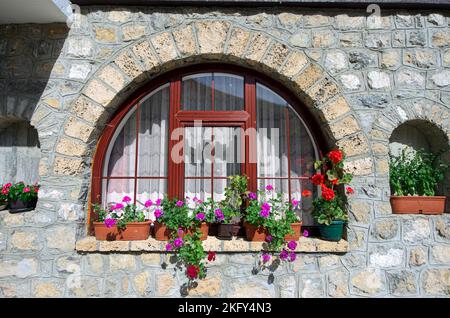 Muro di pietra, finestra ad arco e fiori in vaso del monastero di Kumanica in Serbia Foto Stock