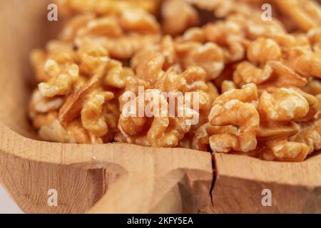 Nocciole di noce pelate in una ciotola di legno rustico spaccata. Nocciole secche. Macro Foto Stock
